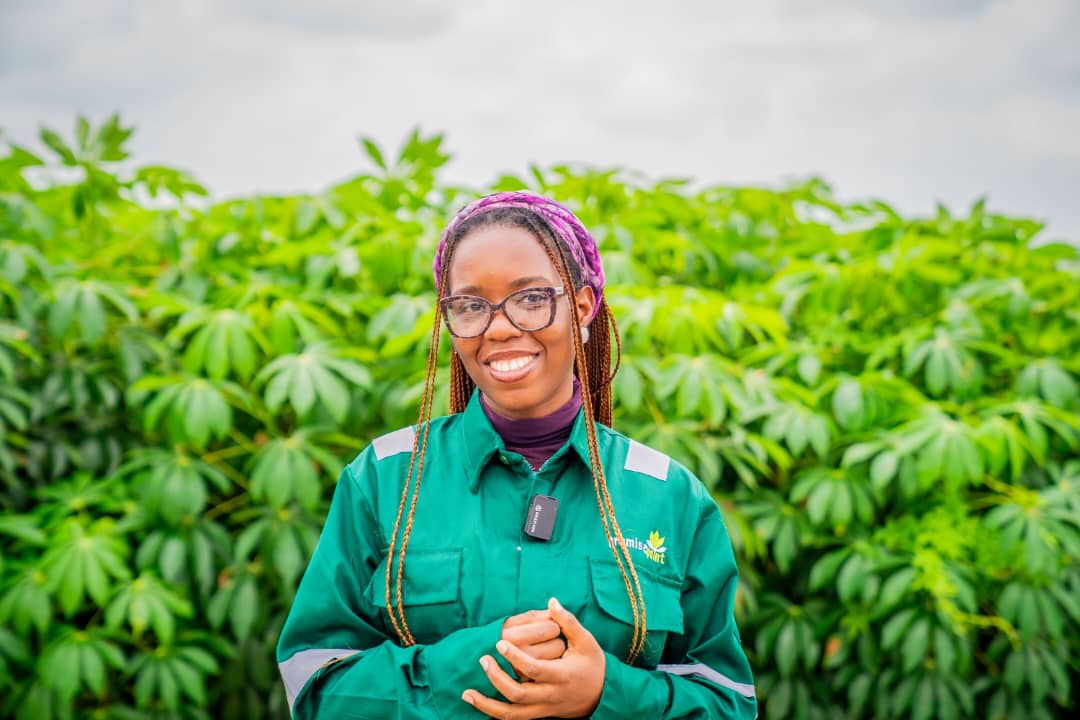 A Promise Point team member in uniform standing in front of a cassava field